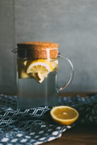 Glass jug filled with water and lemon slices with a cork lid